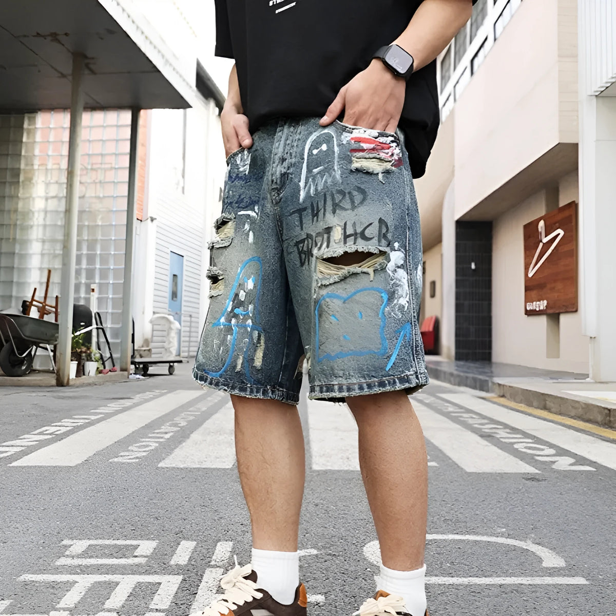 Blue mens denim shorts with ripped knees and graffiti design, straight leg fit.