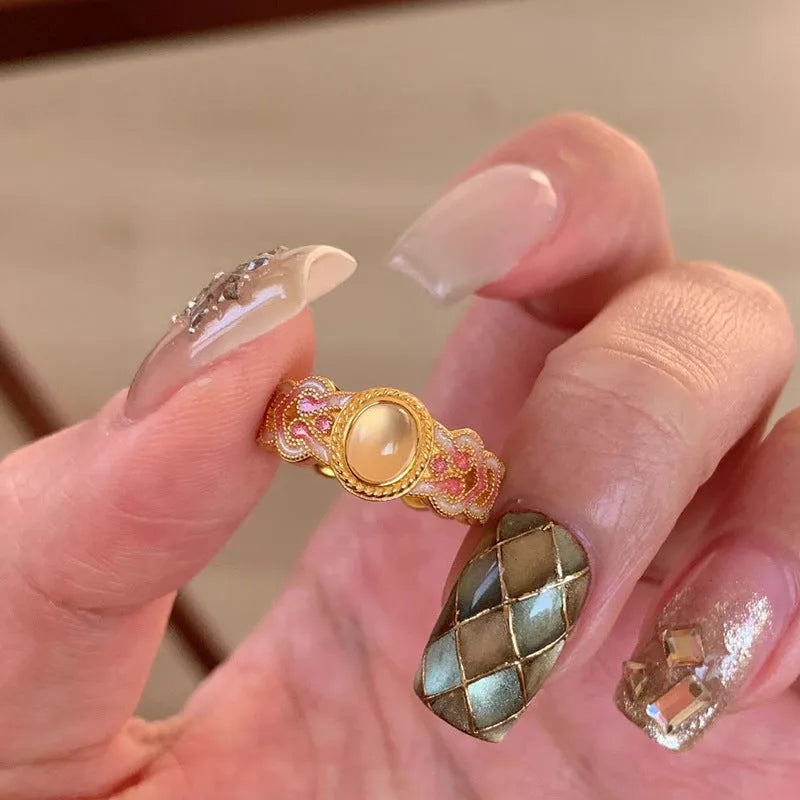Open-mouth geometric women's ring with gold plating and pink crystal enamel detail on a white background.