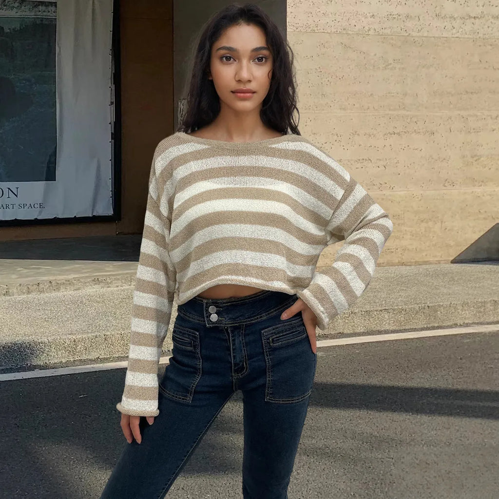 Black and white striped cropped sweater with long sleeves on a woman, showing exposed navel detail.