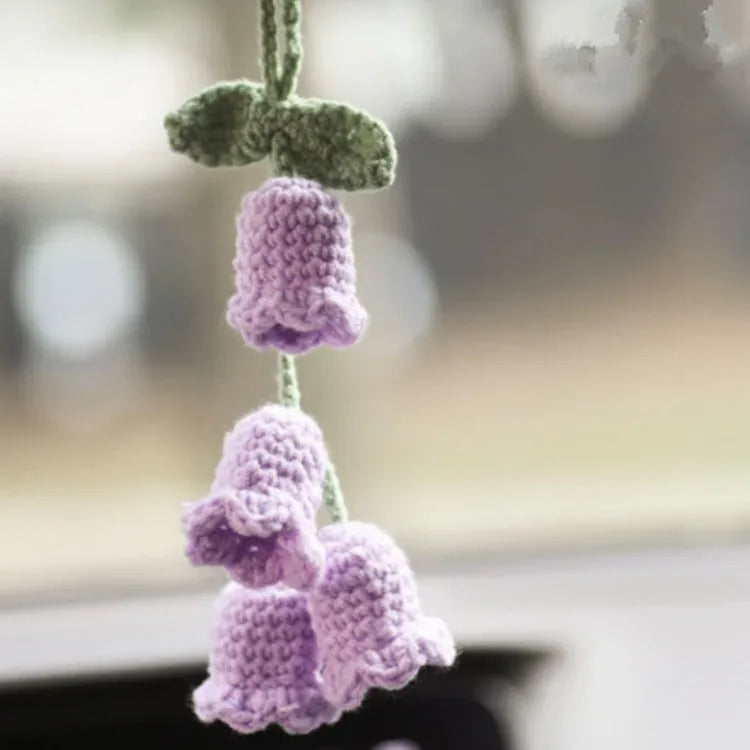 Green and white knitted car plant decoration with hanging rope on car dashboard