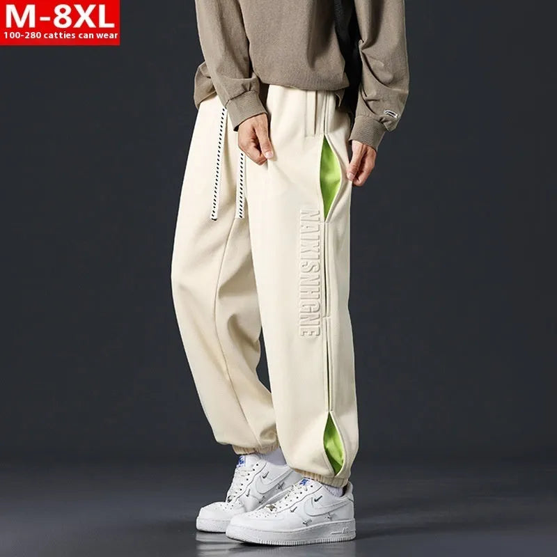 Man wearing loose grey-green cotton trousers with a banded ankle cuff and stitching detail.