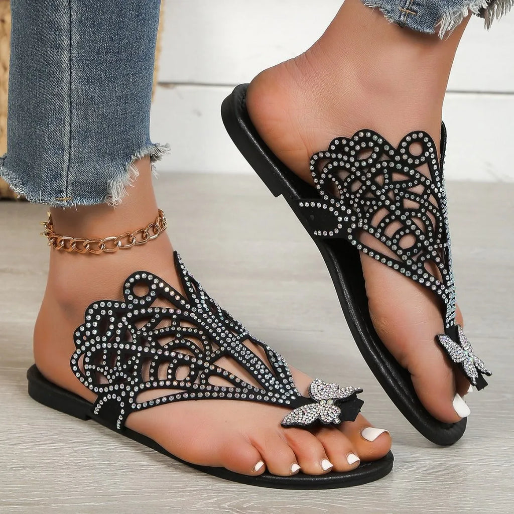 Women's black slip-on sandals with rhinestone detail on flip-toe hollow design and flat rubber sole