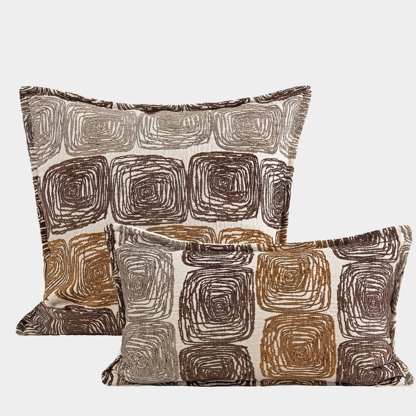 Square and rectangular pillow covers with cream and coffee abstract coil pattern on a sofa.