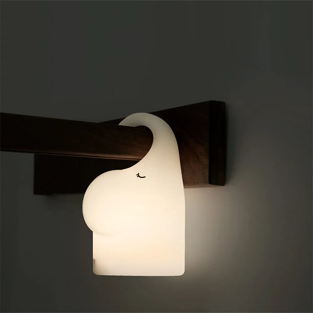 DOMI Elephant-shaped silicone night light in white with warm LED glow on a bedside table.