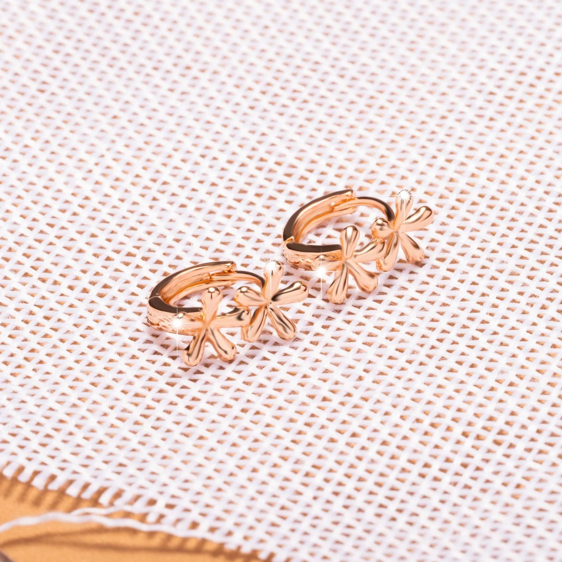 Rose gold coloured circular stud earrings with a detailed waterdrop floral design.