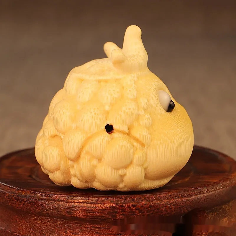 Close-up of a hand-carved bamboo Crown Princess toad ornament with live eye detailing.