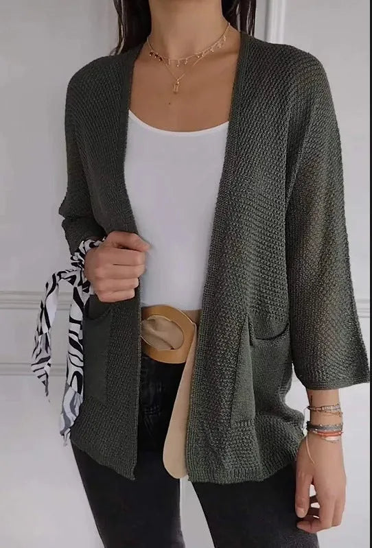 Women's army green waffle knit cardigan coat with nine-quarter sleeves and pockets laid flat.