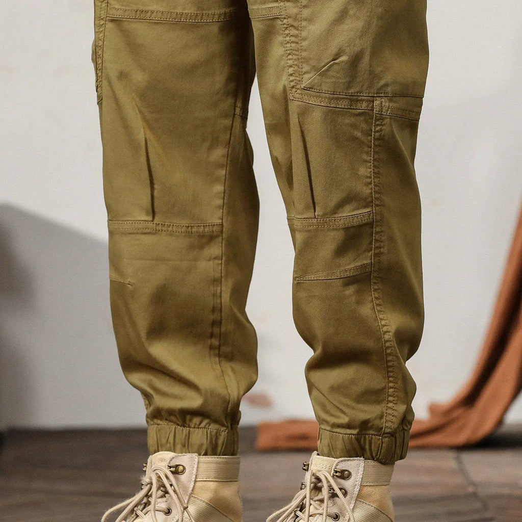 Men's khaki coloured loose-fit tapered harem pants with a small ankle band and elasticated waist.