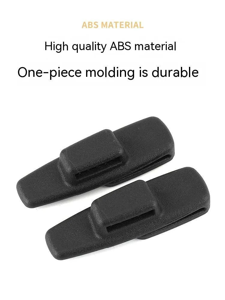 A pair of black plastic universal seat belt stopper clips on a car seat.