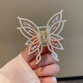 Butterfly-shaped alloy hair clip for women with electroplated finish, shown in rhinestone and pearl styles.