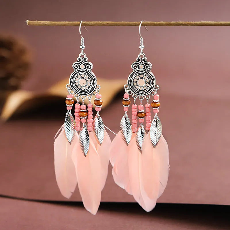 Close-up of a pair of bohemian-style feather-shaped earrings with a leaf pattern, in an alloy electroplated finish.