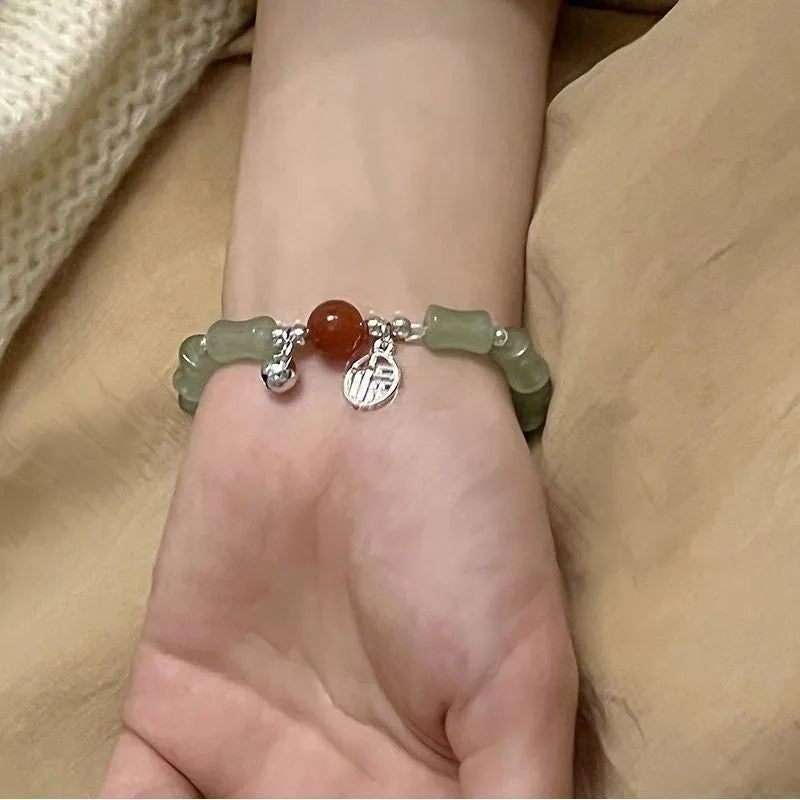A Chinese style glass bracelet with bamboo leaf and bead designs on a wrist.