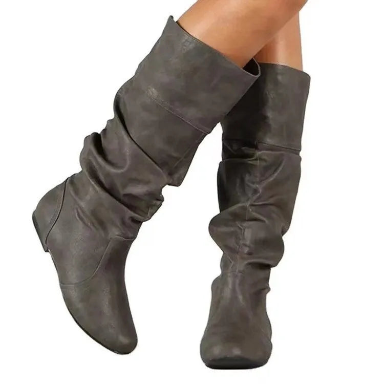Women's black slip-on flat long boots with a round toe and high shaft on a neutral background.
