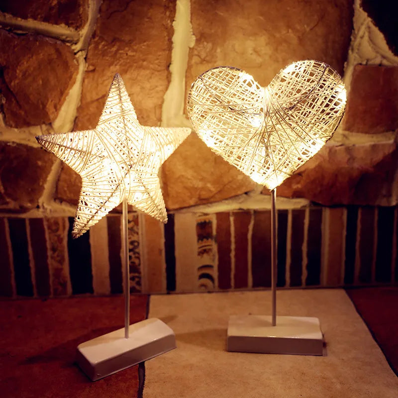 Rattan and copper wire LED table lamp in a star shape on a bedside table.