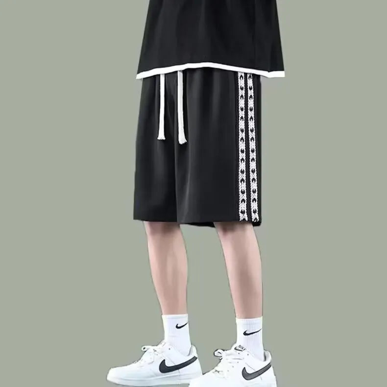 Men's loose-fitting black baggy track pants with a sports style on a plain background.