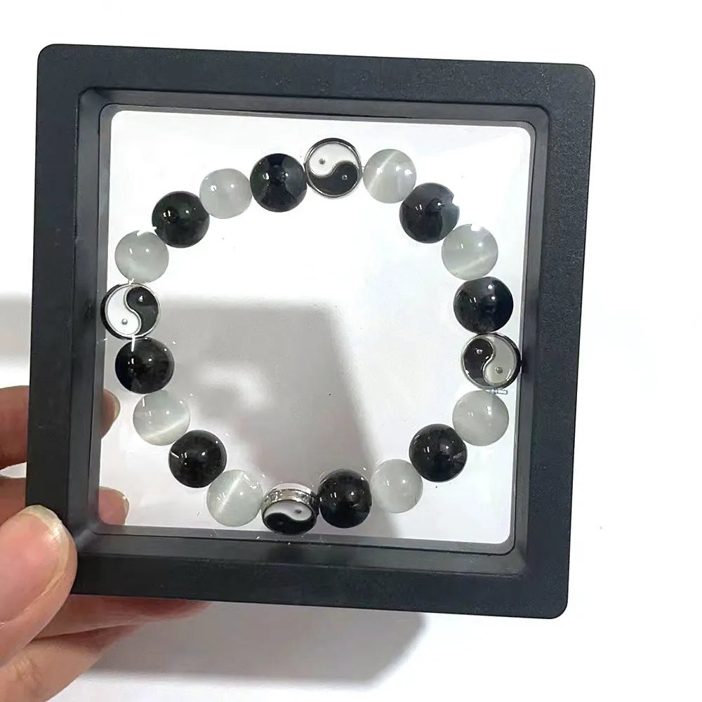 Close-up of a polished opal agate Tai Chi bracelet with a black agate yin-yang symbol on a wrist.