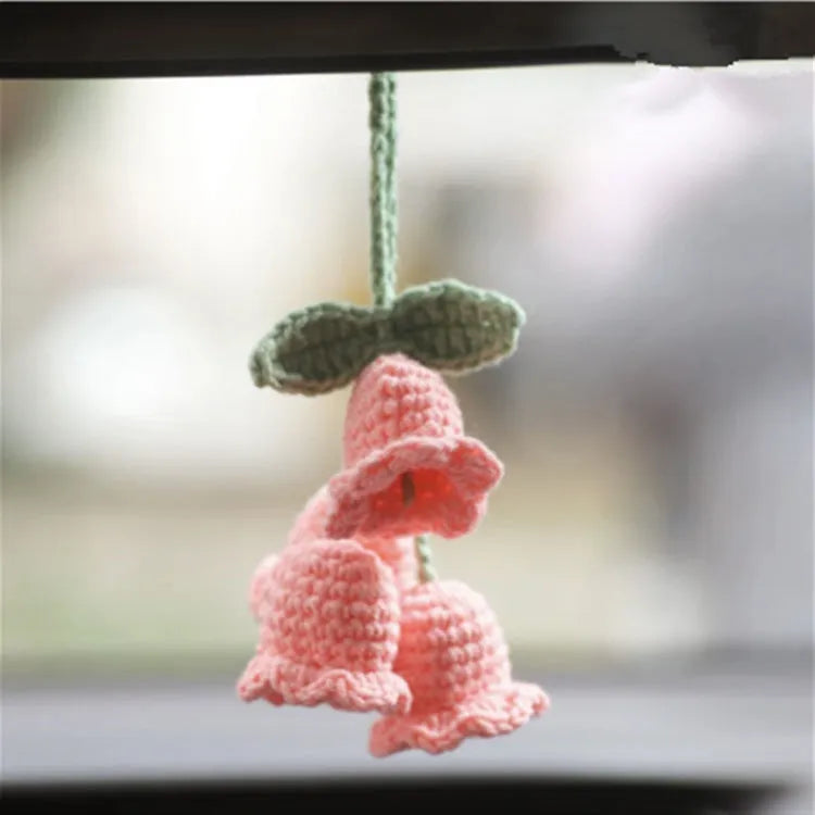 Green and white knitted car plant decoration with hanging rope on car dashboard