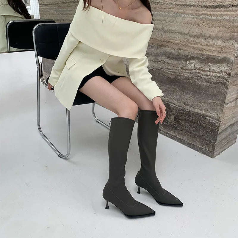 Black women's pointed toe below-the-knee boots with a stiletto heel and a back zipper closure on the side.