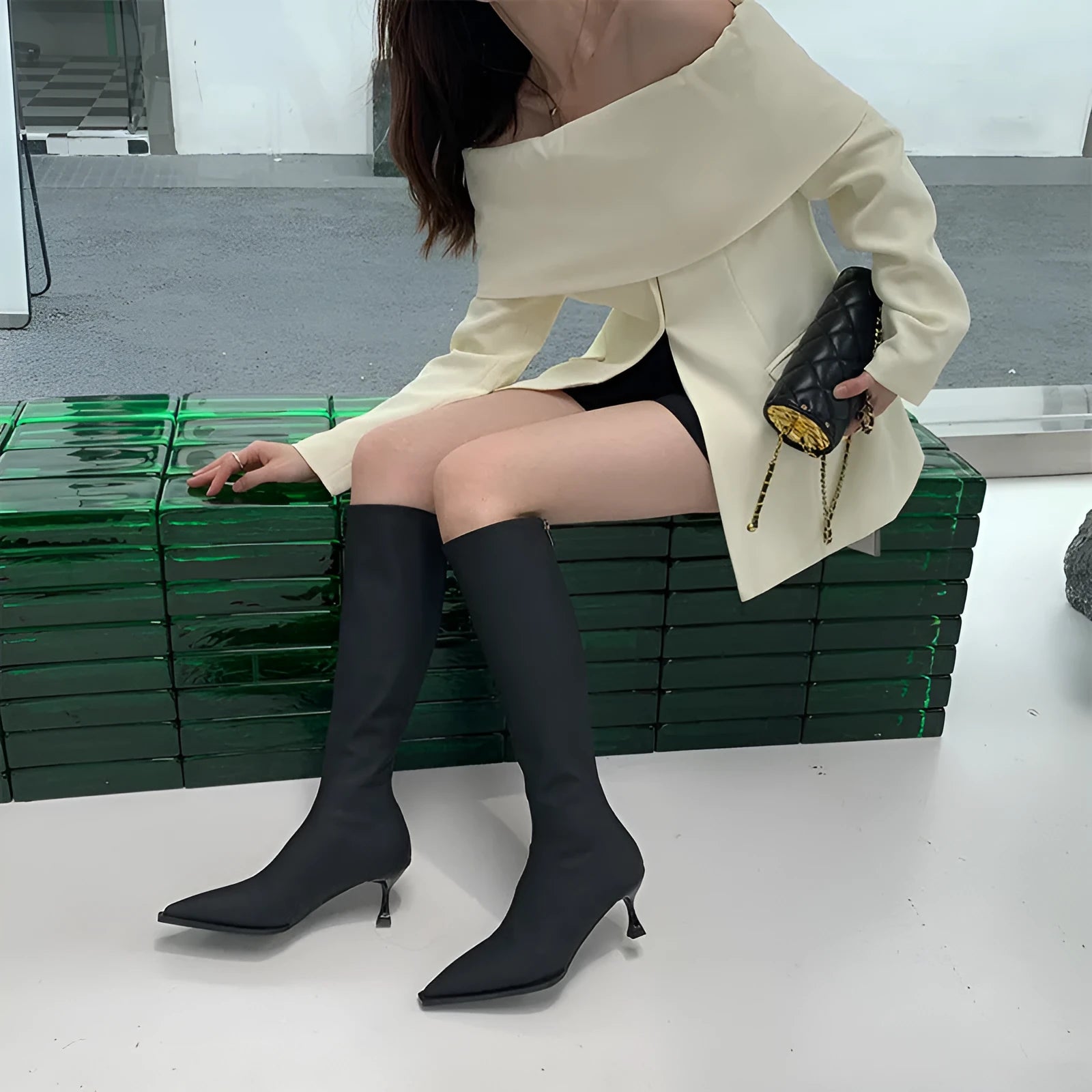 Black women's pointed toe below-the-knee boots with a stiletto heel and a back zipper closure on the side.
