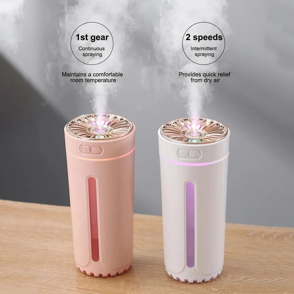 Black portable USB rechargeable car humidifier with colourful lights on a desk next to a cup