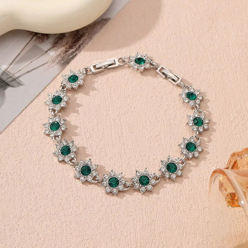 Gold tone flower-shaped bracelet with blue crystal gems on a wrist.