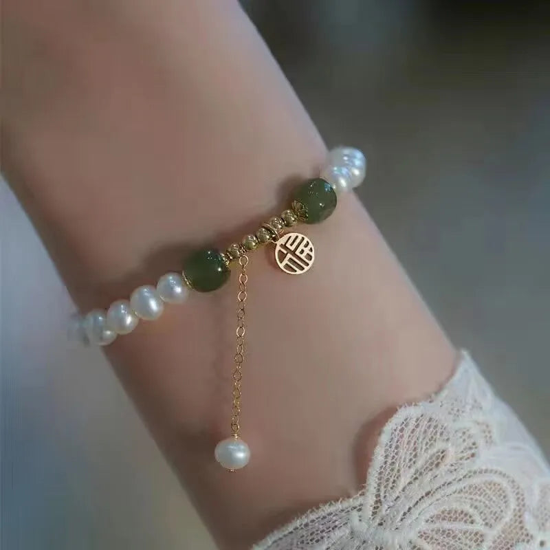 A Chinese style glass bracelet with bamboo leaf and bead designs on a wrist.