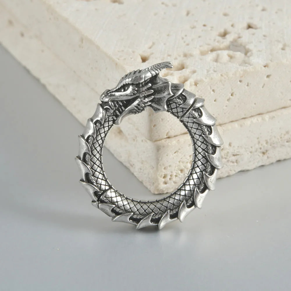 A pair of large, geometric dragon-shaped hollow out earrings in an antique silver colour.