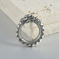 A pair of large, geometric dragon-shaped hollow out earrings in an antique silver colour.