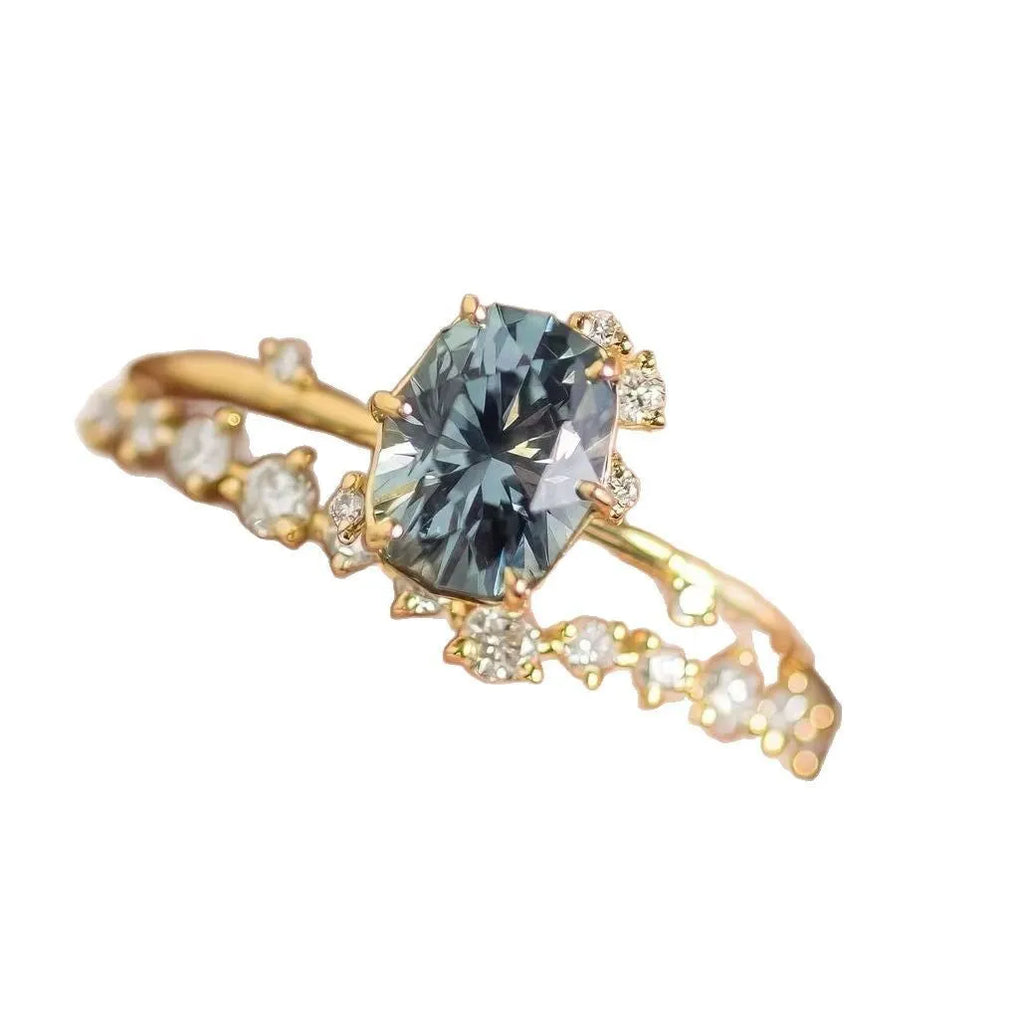Gold-plated floral ring with a green zircon stone, shown on a finger.