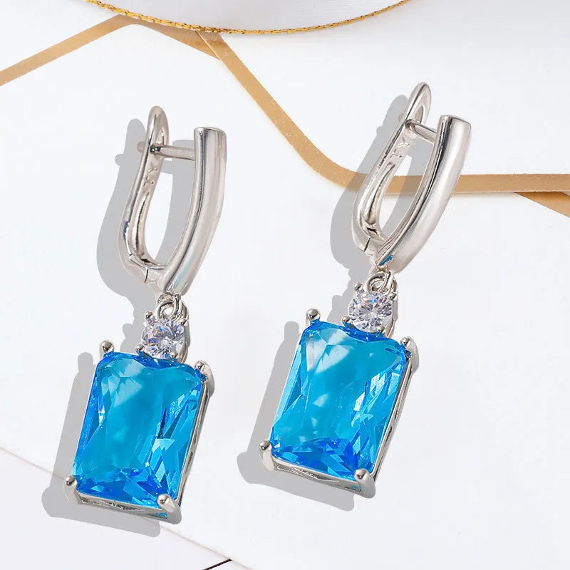 A pair of square geometric earrings with an electroplated gold finish on a copper base.