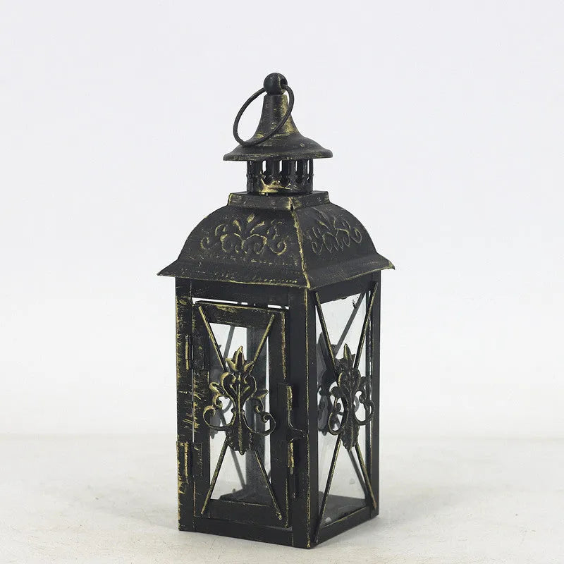 Black wrought iron floor lantern with tempered glass panels, standing on a patio.
