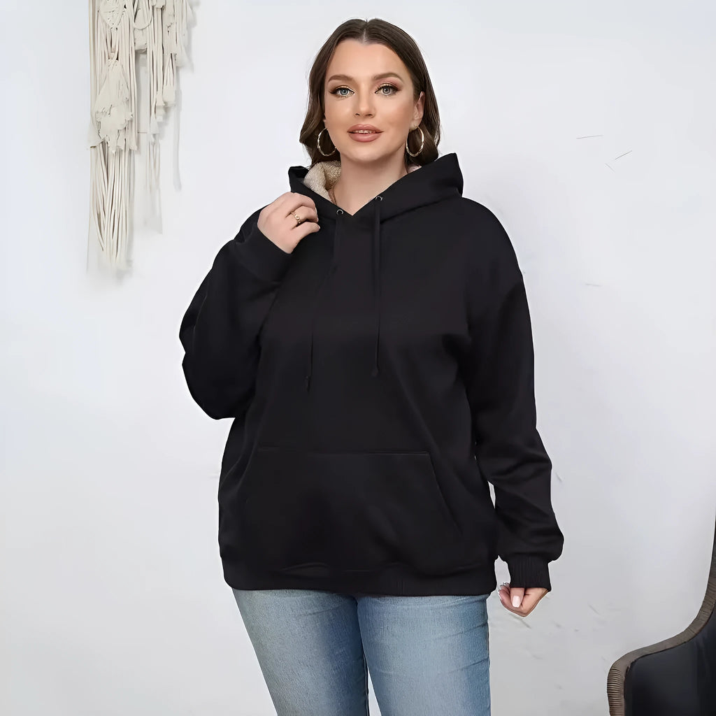 Woman wearing a thick, grey hooded sweater with a raised 3D pattern, featuring long sleeves and pockets.