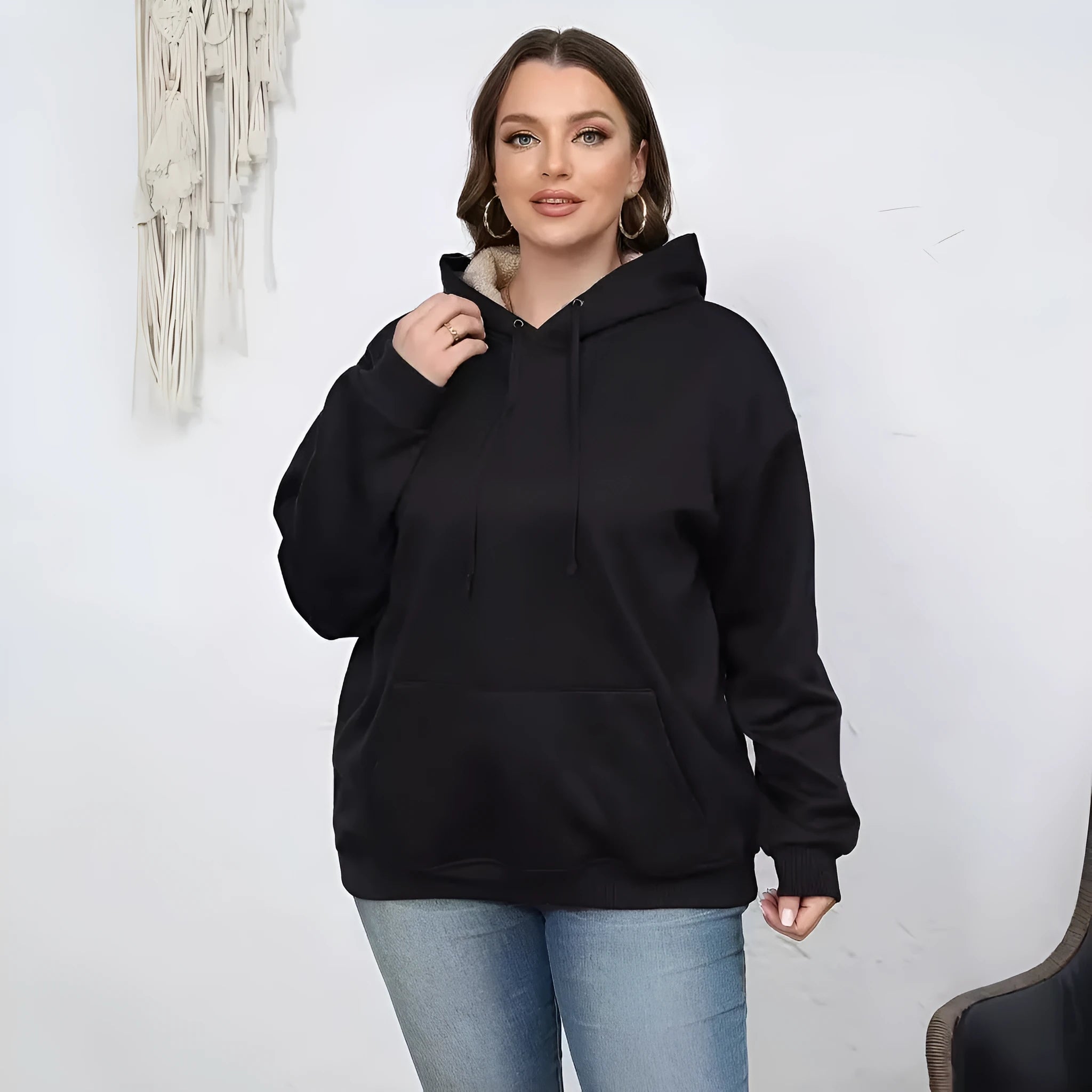 Woman wearing a thick, grey hooded sweater with a raised 3D pattern, featuring long sleeves and pockets.