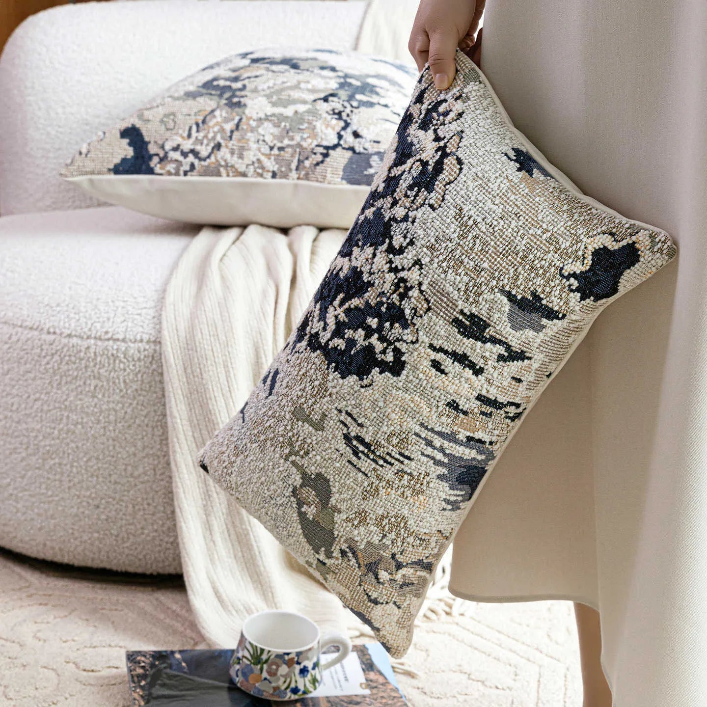 Antique blue French style decorative pillow with abstract floral pattern on a sofa.
