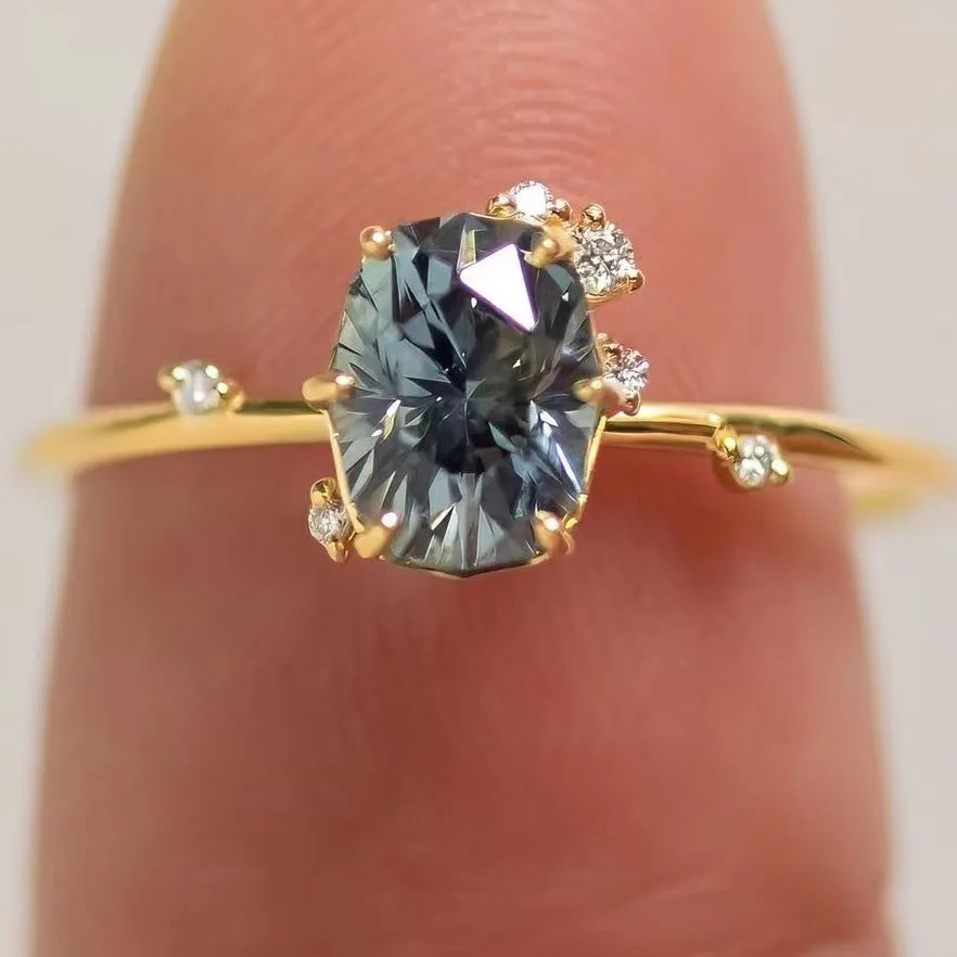 Gold-plated floral ring with a green zircon stone, shown on a finger.