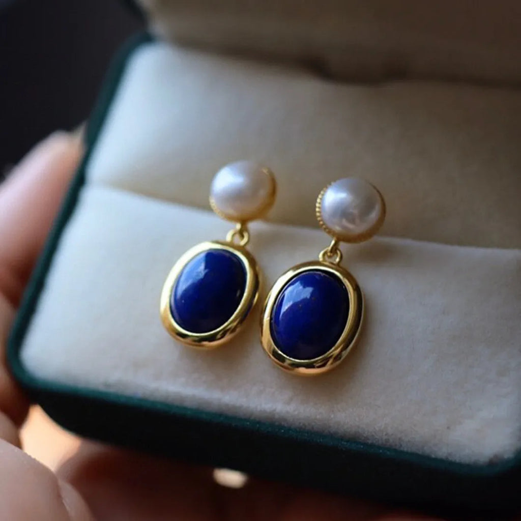 A pair of simple stud earrings featuring a deep blue lapis lazuli pearl set in 925 silver.