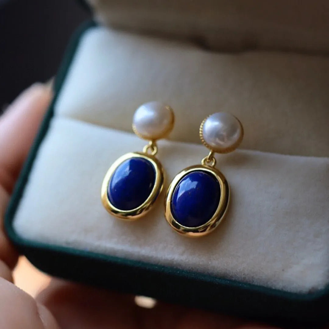 A pair of simple stud earrings featuring a deep blue lapis lazuli pearl set in 925 silver.