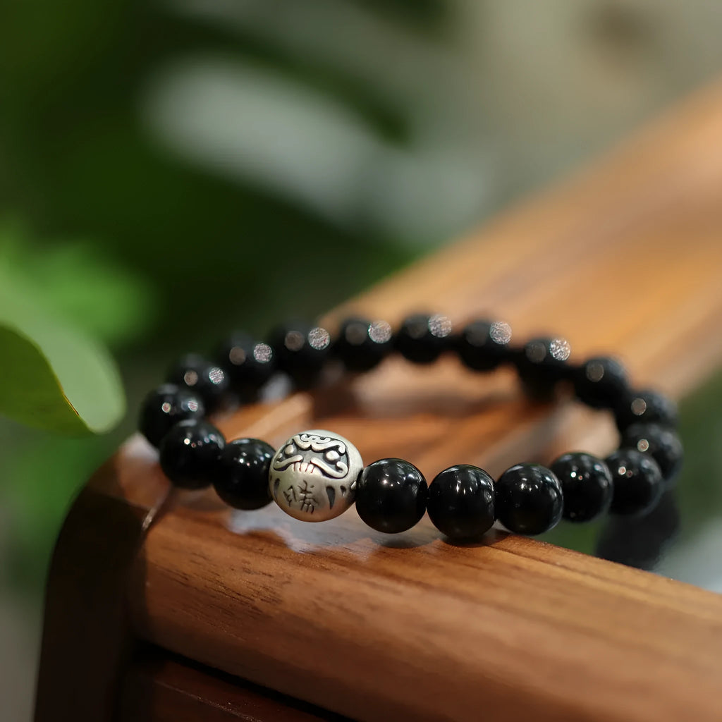 Close-up of a black agate bead bracelet with a sterling silver clasp on a wrist.