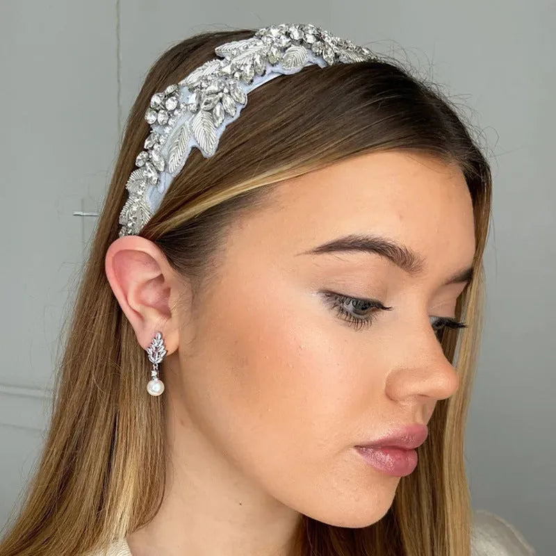 Geometric flower shaped earrings with micro inlaid zircon stones and pearl accents on a gold plated background.