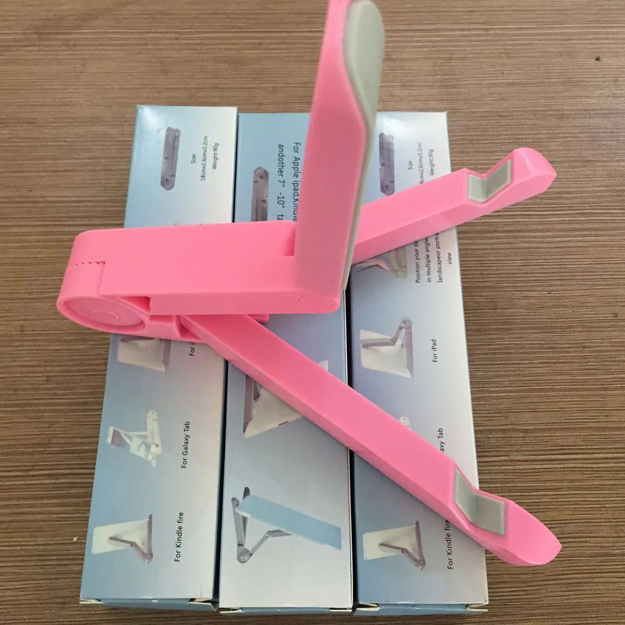 Black foldable tablet holder open in landscape mode holding a smartphone, showing its adjustable angle and non-slip base.