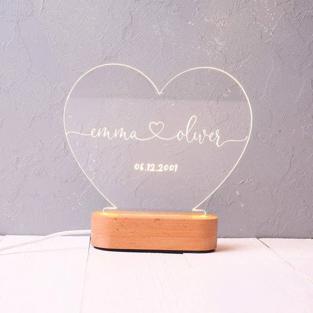 Custom clear acrylic night light with engraved names, lit by an LED base.