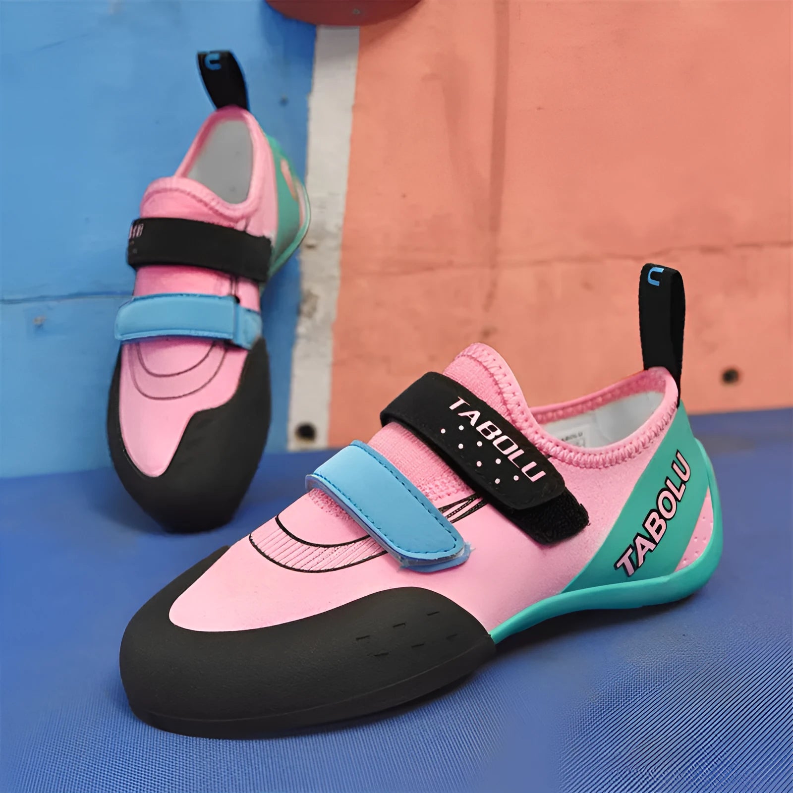 Black beginner rock climbing shoes with Velcro straps and a coloured accent on a rubber sole.