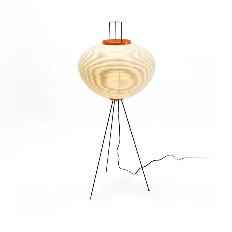 Japanese style table lamp with a white handmade paper lantern shade and aluminium base on a wooden table.