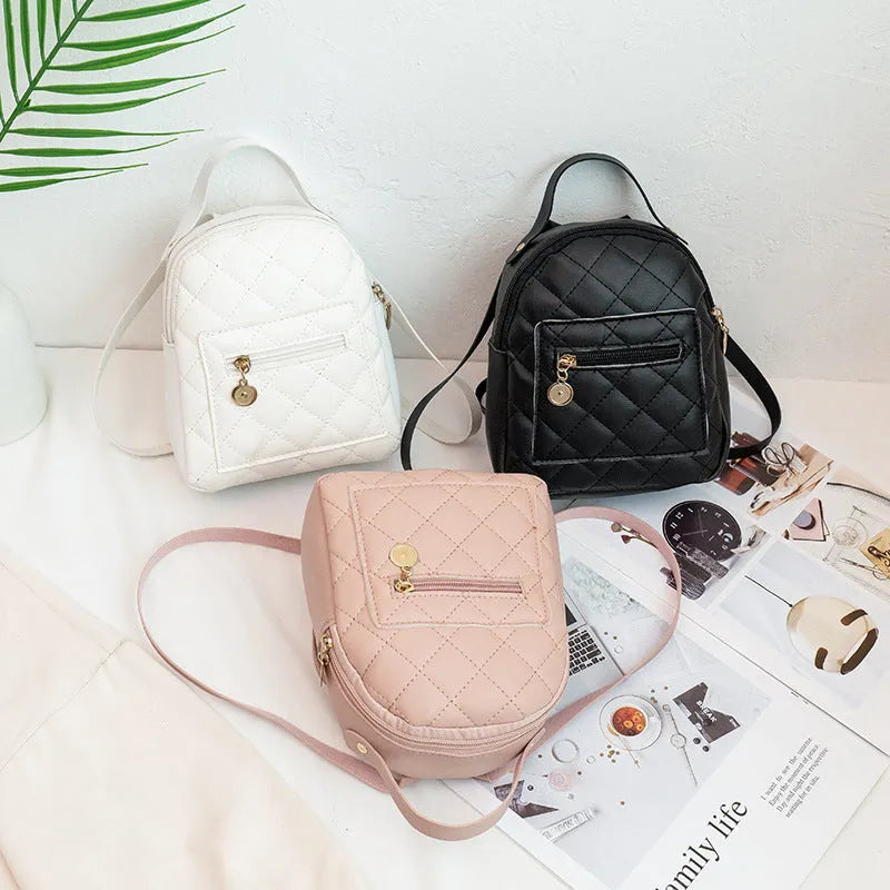 Hard-sided square pink backpack with embroidered detail, shown with soft carry handle and straps.