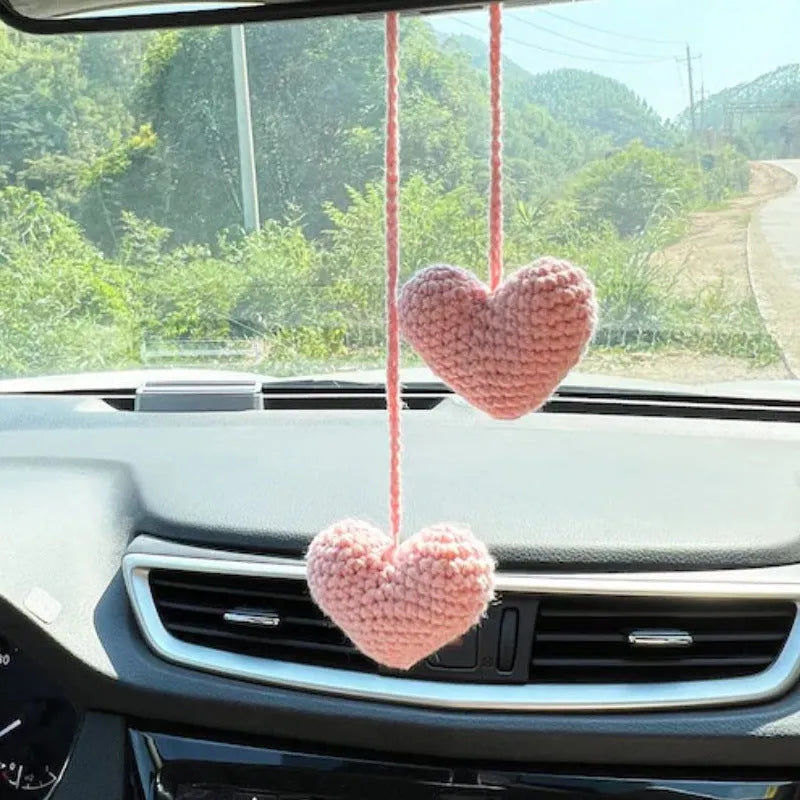 Green and white knitted car plant decoration with hanging rope on car dashboard
