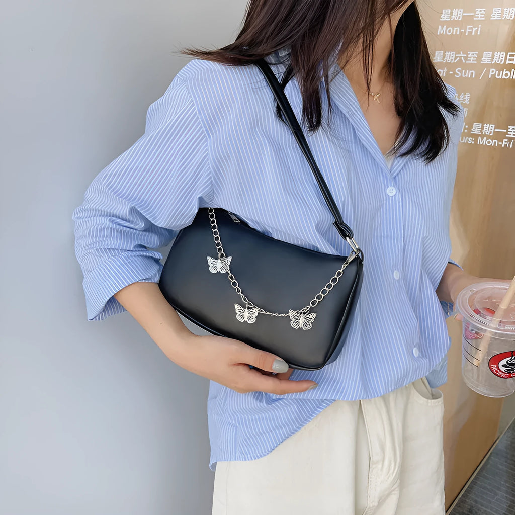 Women's black butterfly design chain underarm bag with a squared shape and three-dimensional pocket.