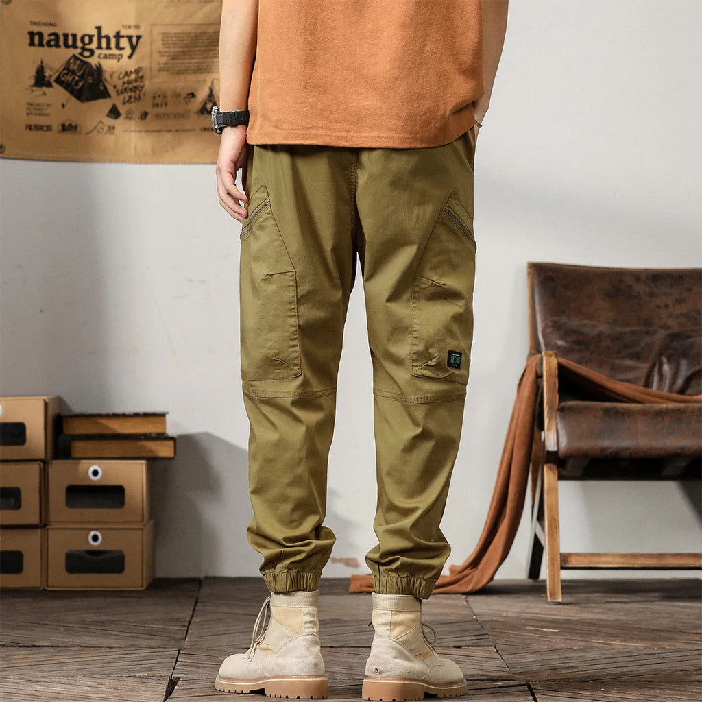 Men's khaki coloured loose-fit tapered harem pants with a small ankle band and elasticated waist.