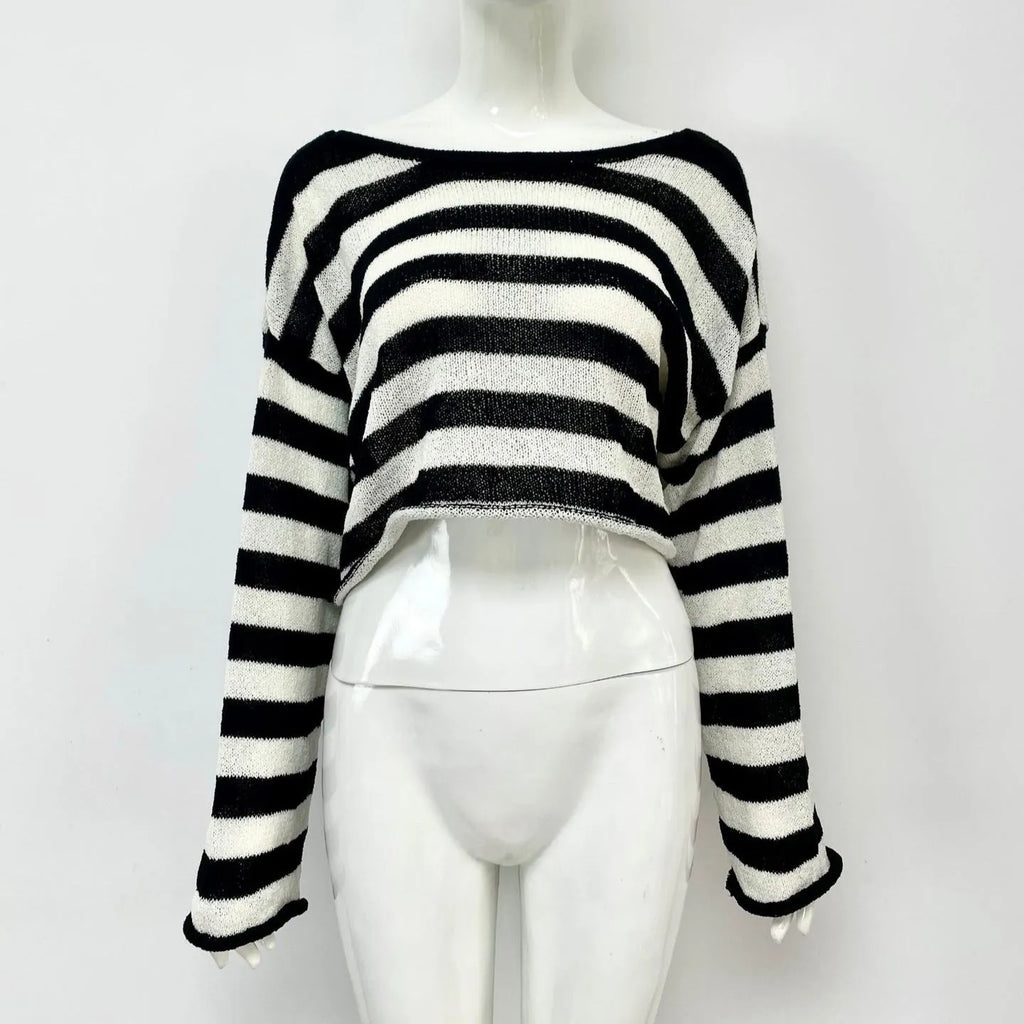 Black and white striped cropped sweater with long sleeves on a woman, showing exposed navel detail.