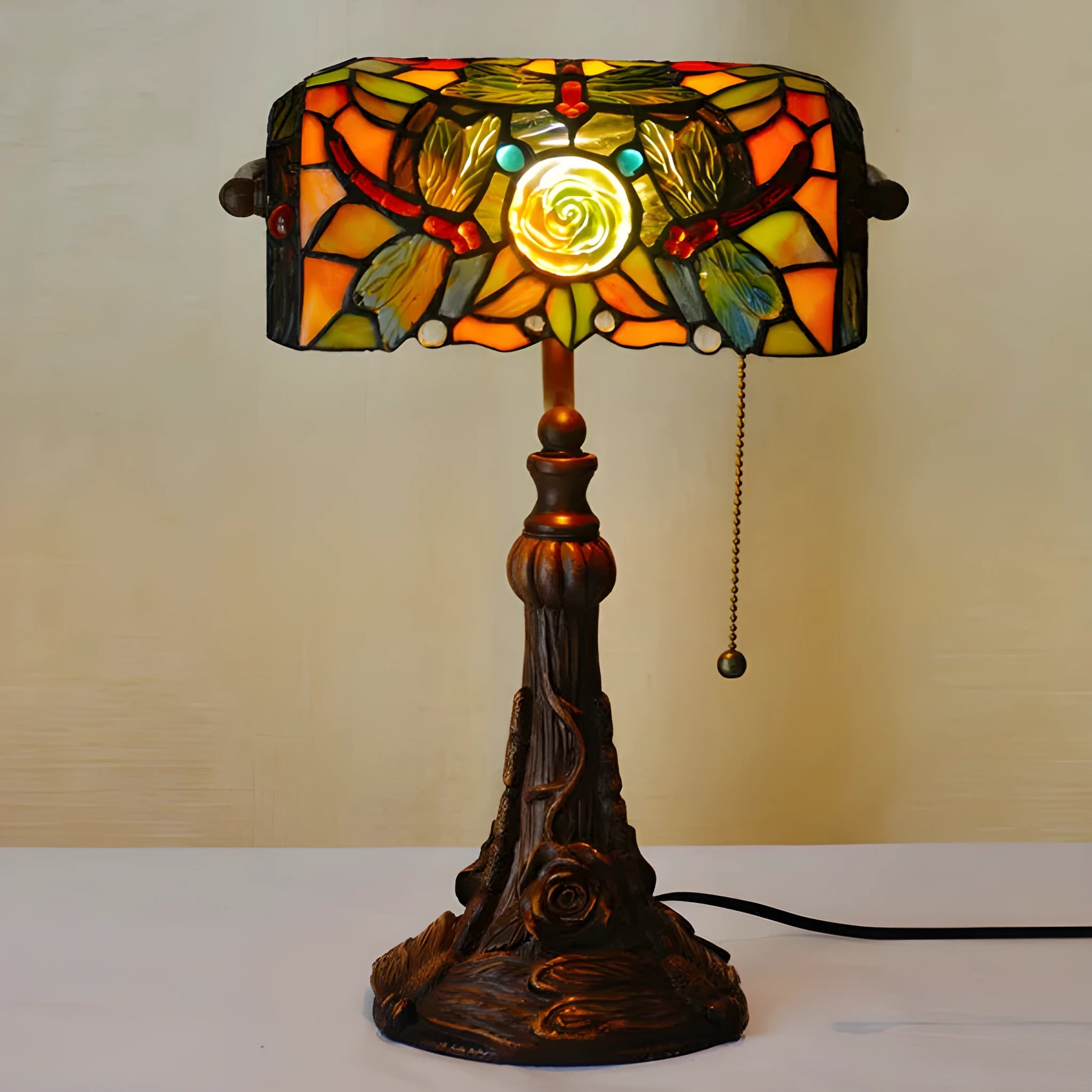10-inch Tiffany style table lamp with coloured stained glass shade and resin base on a desk.