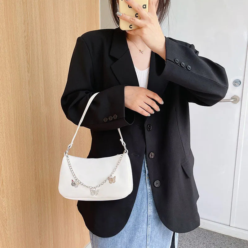 Women's black butterfly design chain underarm bag with a squared shape and three-dimensional pocket.
